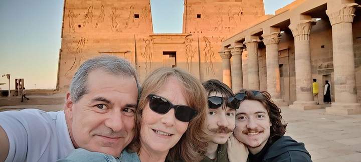 Family taking a selfie in front of the sunlit pylon at Philae Temple, Aswan