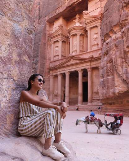 Traveler sitting on the rocks in front of the Treasury at Petra, Jordan