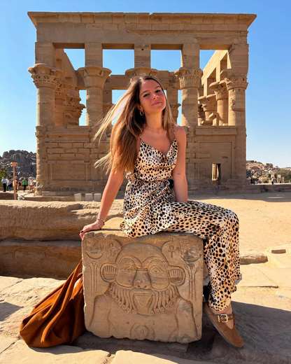 Traveler seated on a carved block in front of the Kiosk of Trajan at Philae Temple, Aswan