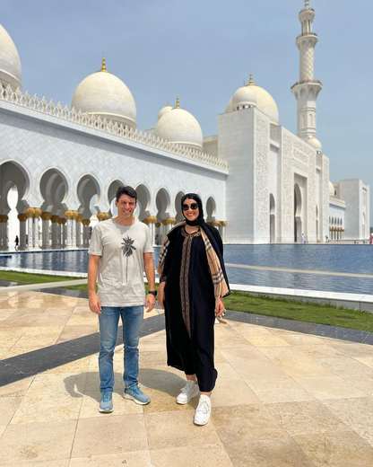 Couple standing by the reflecting pool at the Sheikh Zayed Grand Mosque, Abu Dhabi